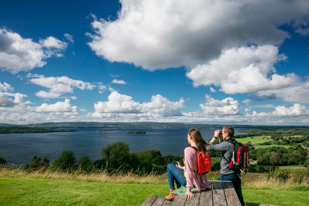 a man and woman on a picnic bench looking out over Lough Derg